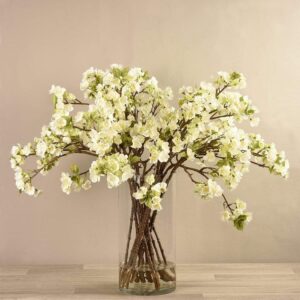 أغصان زهور صناعية داخل مزهرية زجاجية