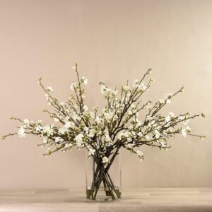 أغصان أشجار مزهرة صناعية في مزهرية زجاجية